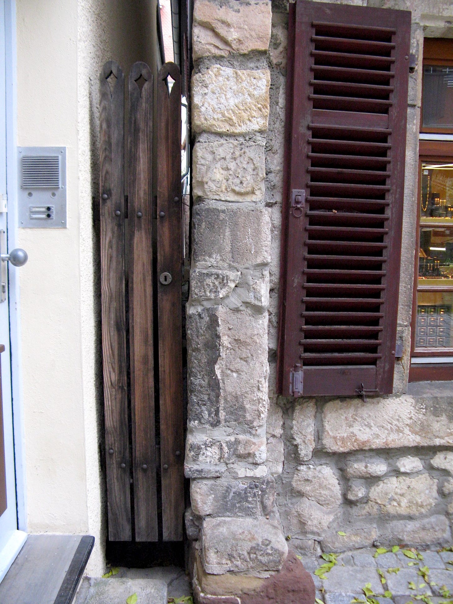 Narrow gate about a foot wide, with lock, between two buildings