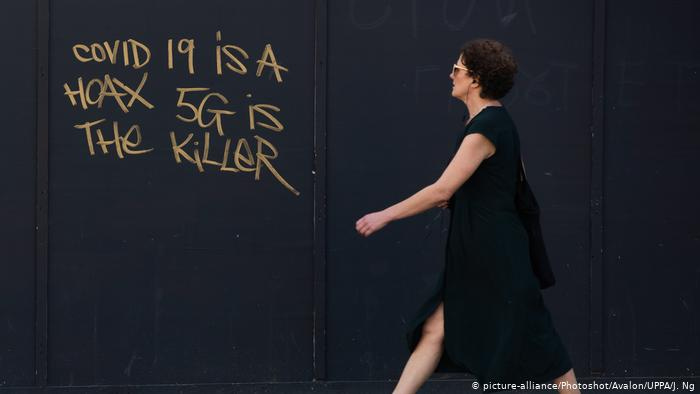 A woman walks past graffiti stating COVID-19 is a hoax 5G is the killer in London A woman walks past graffiti stating COVID-19 is a hoax 5G is the killer in London