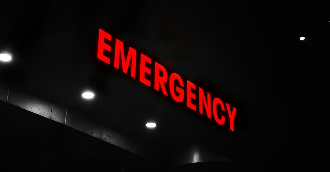 Red emergency sign illuminates a dark building entrance. Red emergency sign illuminates a dark building entrance.