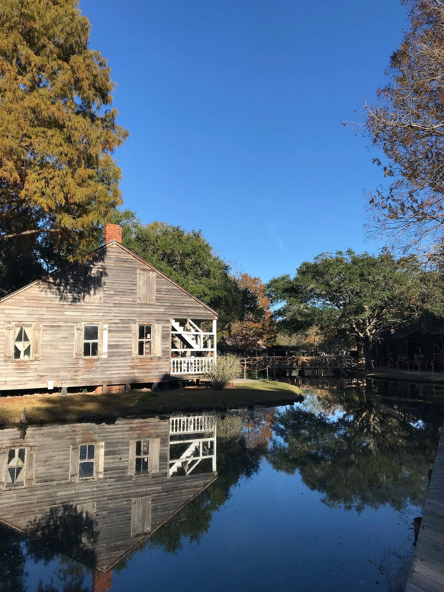  Reflections of a wooden cabin from LARC’s Arcadian Village in Lafayette, LA 