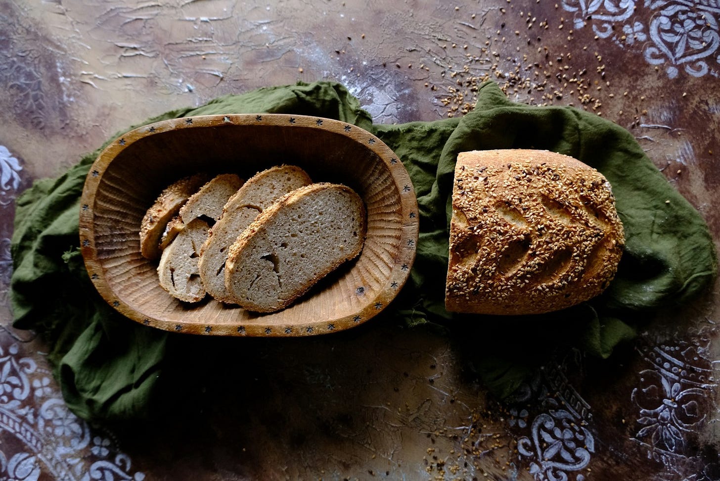 a wooden bowl filled with bread next to a loaf of bread a wooden bowl filled with bread next to a loaf of bread