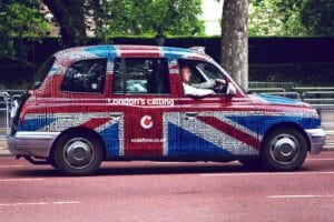 man driving a taxi covered in the Union Jack image