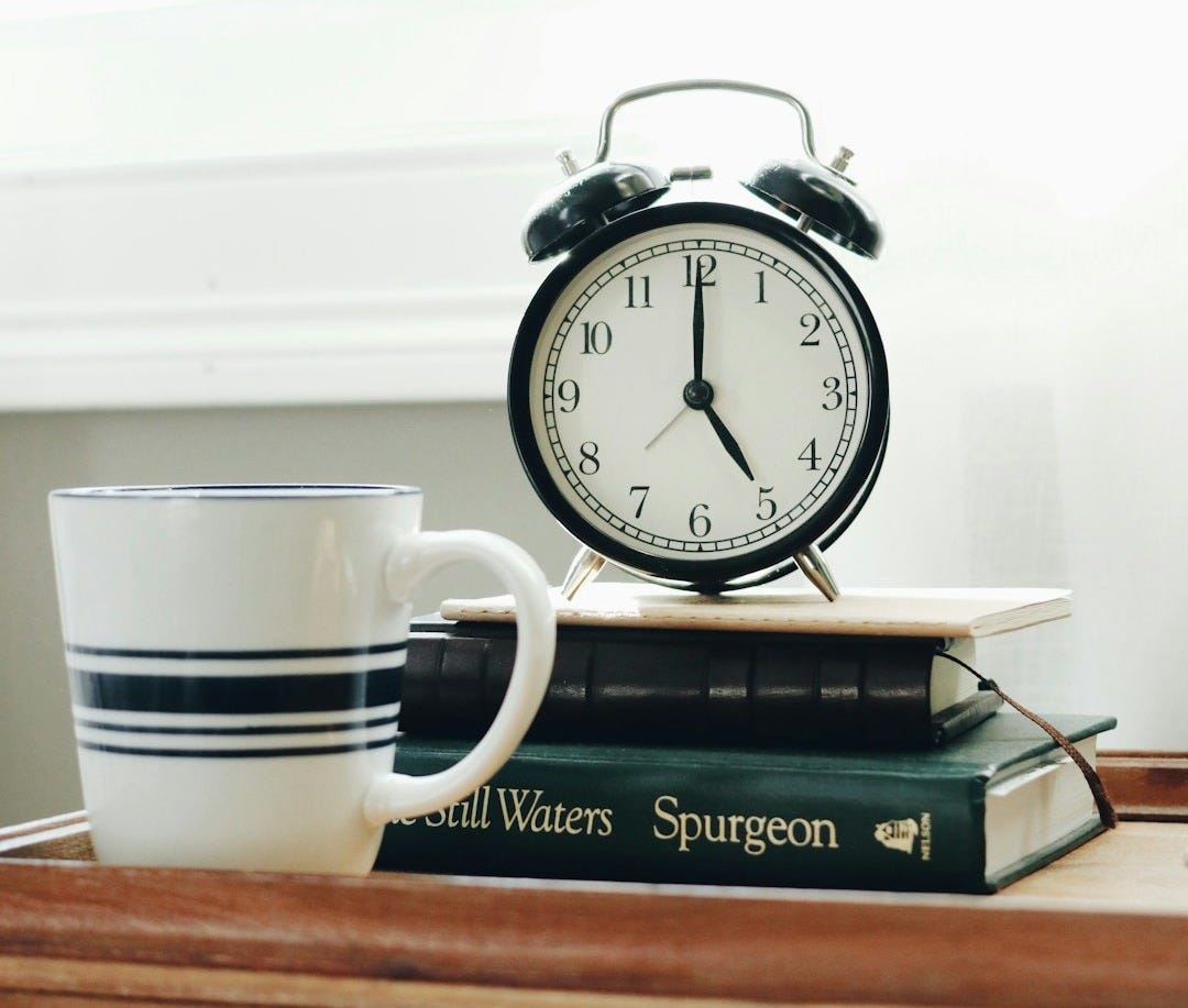 white ceramic mug beside white and black analog alarm clock white ceramic mug beside white and black analog alarm clock