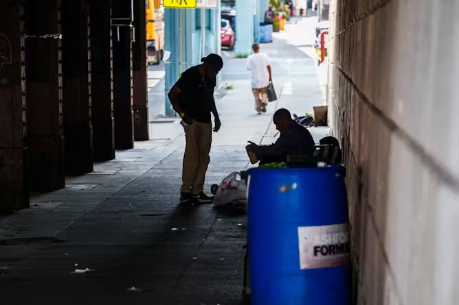 Two men in shadow speak in dimly lit area