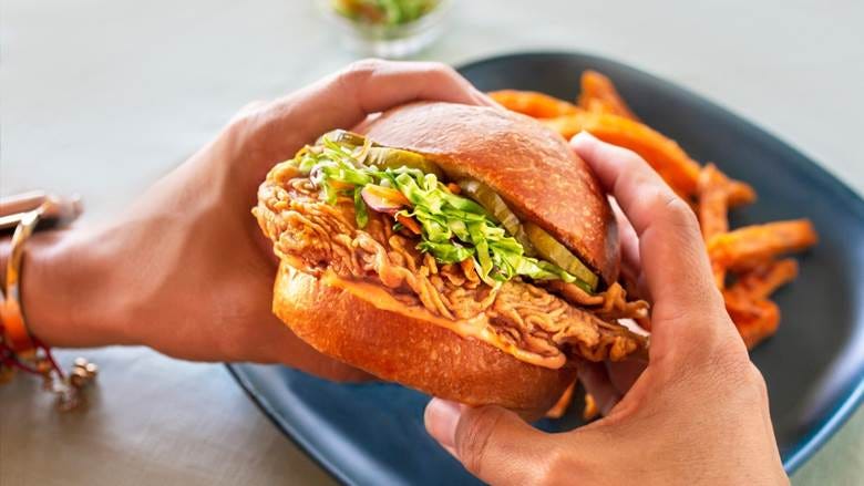 A person holding a sandwich

Description automatically generated