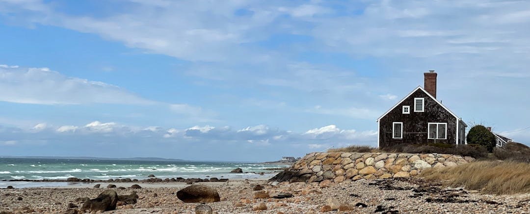 a house sitting on top of a sandy beach next to the ocean