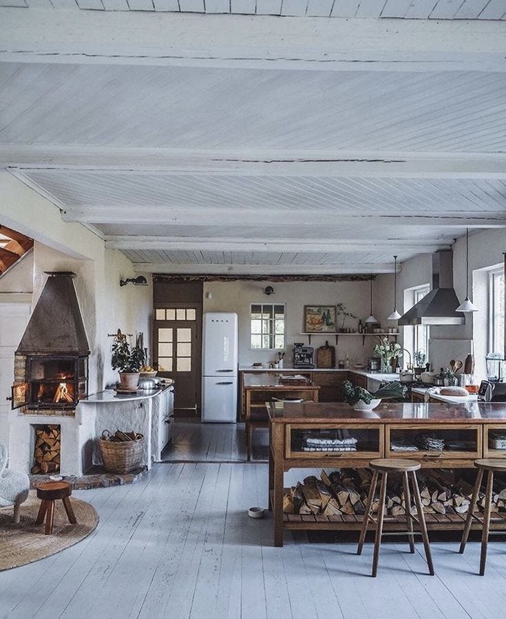 This may contain: an open kitchen and dining area with wood burning stoves in the center, surrounded by white painted walls This may contain: an open kitchen and dining area with wood burning stoves in the center, surrounded by white painted walls