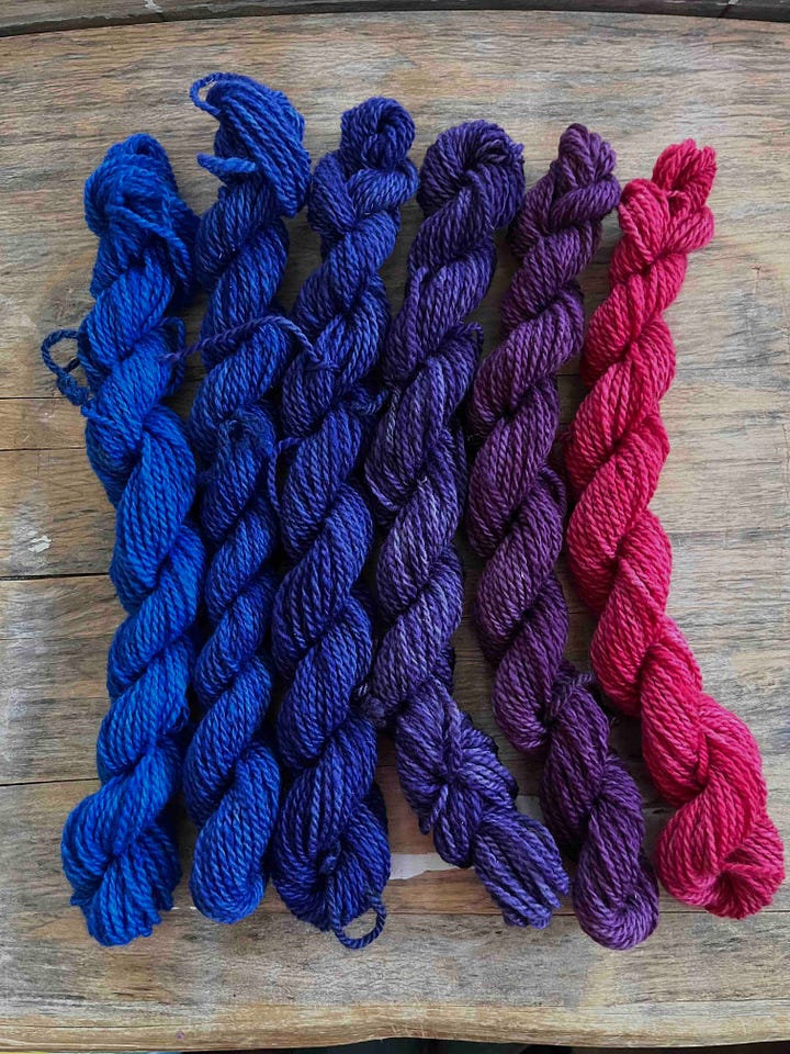 Two sets of 6 skeins of yarn, in a gradient from raspberry red to a royal blue. One set is darker.