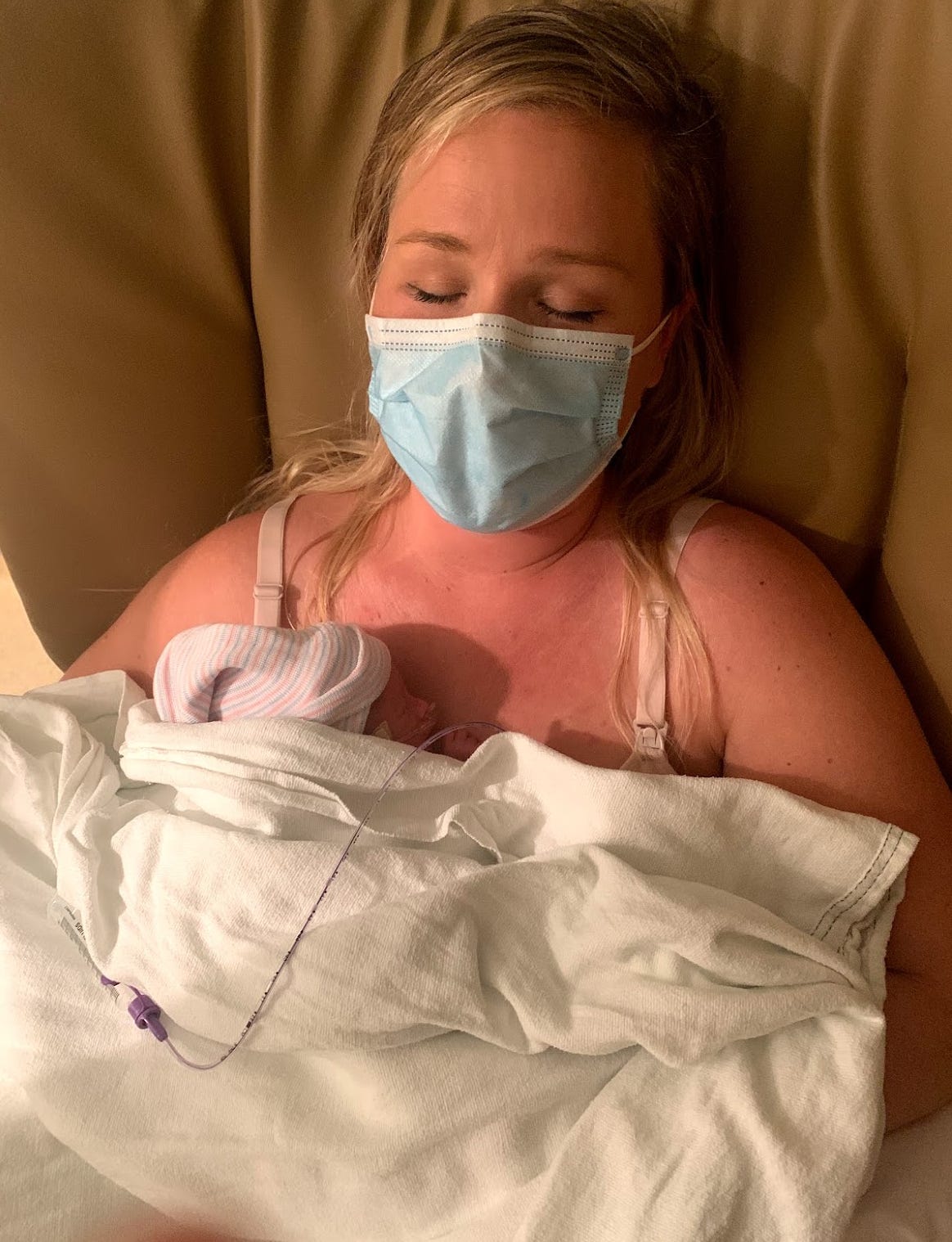 Seana wearing a mask, holding baby Damian close to her chest Seana wearing a mask, holding baby Damian close to her chest