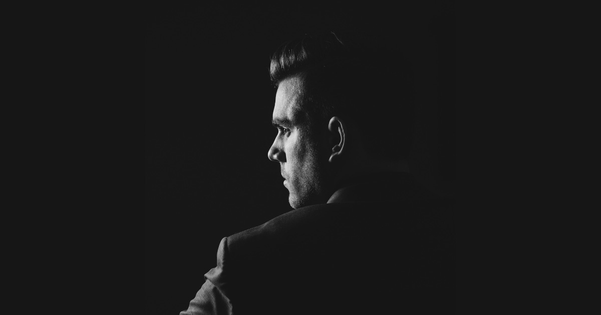 a man seen from behind, head half turned to the camera, in black & white