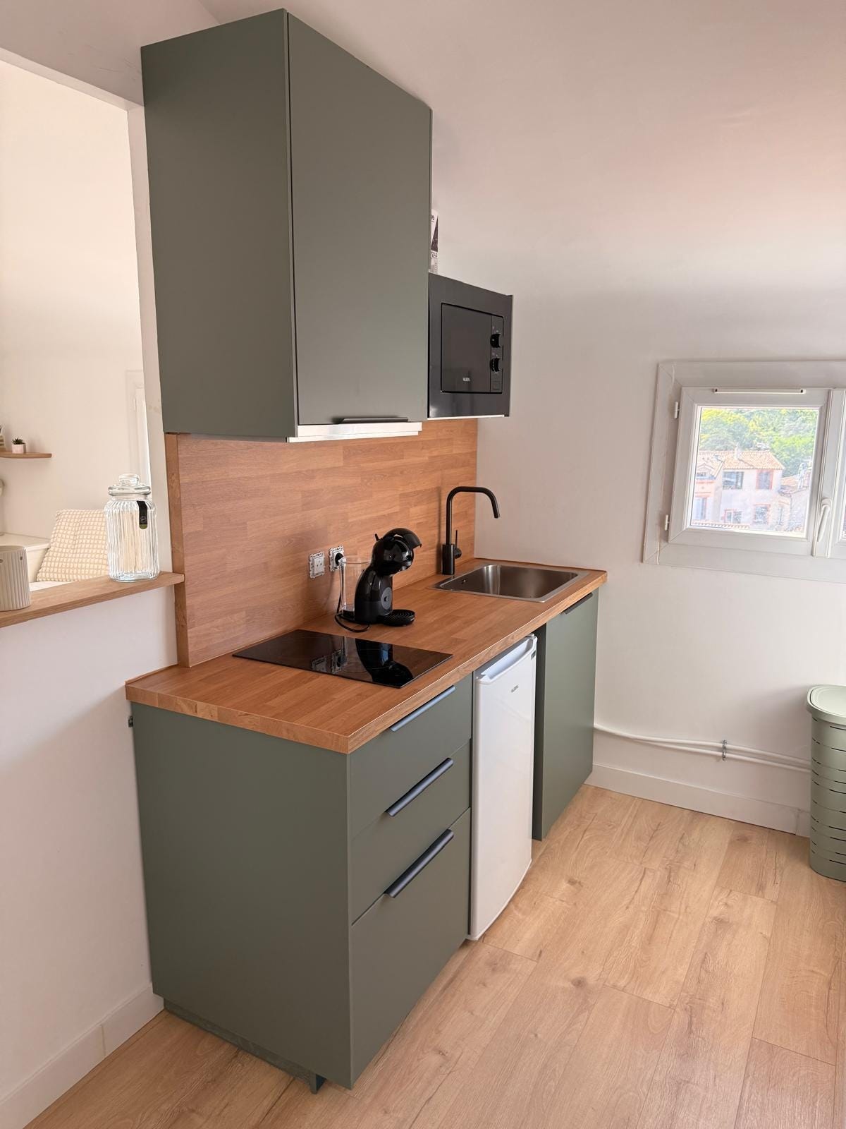 La cuisine entièrement neuve, façades vertes et plan de travail bois, avec vue sur les toits toulousains La cuisine entièrement neuve, façades vertes et plan de travail bois, avec vue sur les toits toulousains