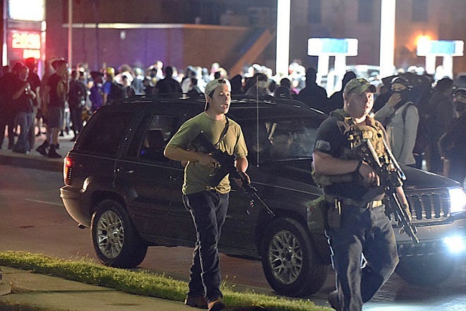 Kyle Rittenhouse, left, with backwards cap, walks along Sheridan Road in Kenosha, Wis., Tuesday, Aug. 25, 2020, with another armed civilian. Prosecutors on Thursday, Aug. 27, 2020 charged Rittenhouse, a 17-year-old from Illinois in the fatal shooting of two protesters and the wounding of a third in Kenosha, Wisconsin, during a night of unrest following the weekend police shooting of Jacob Blake.