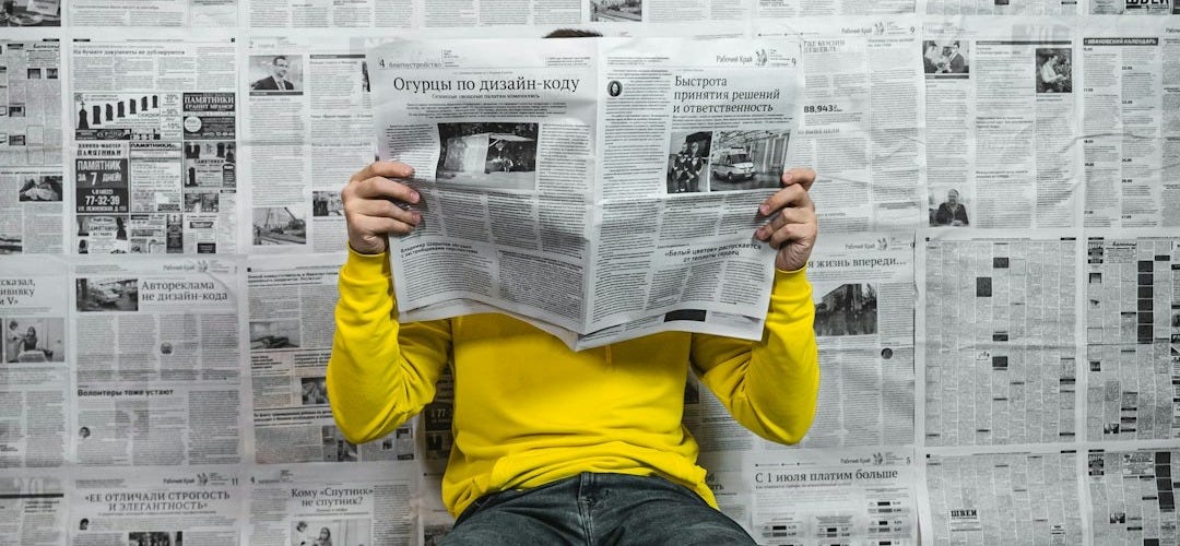 a person sitting on the floor reading a newspaper