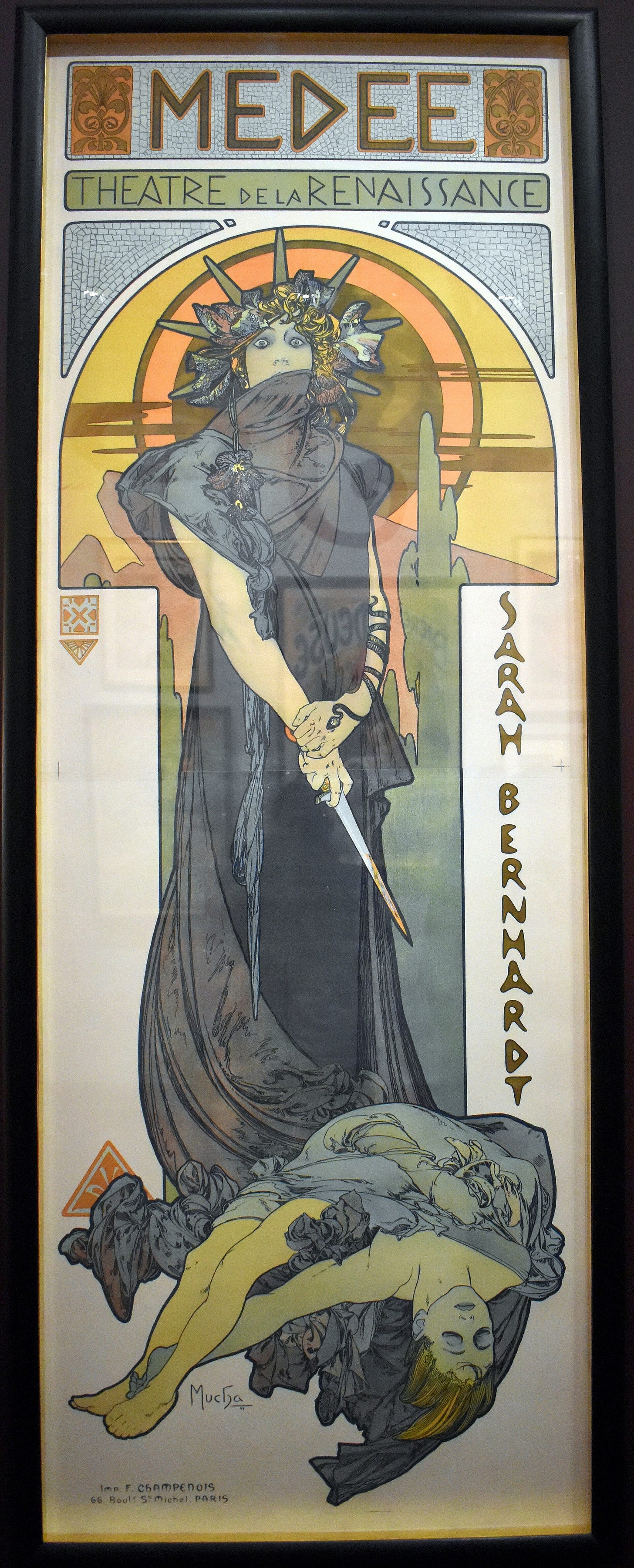 A tall Art Nouveau poster of Sarah Bernhardt as Medea, staring wide-eyed, a dagger in her hand and a gold snake coiled round her arm, a setting sun behind her. A tall Art Nouveau poster of Sarah Bernhardt as Medea, staring wide-eyed, a dagger in her hand and a gold snake coiled round her arm, a setting sun behind her.
