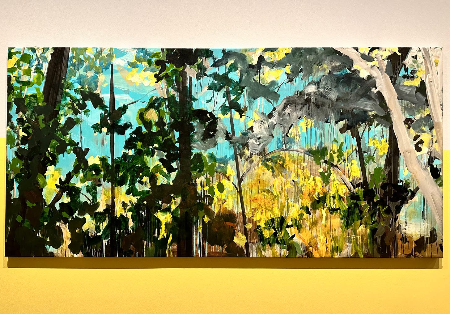 Abstract landscape painting mounted on a lemon yellow wall.