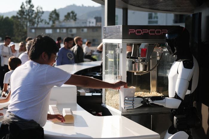 A Tesla Optimus robot serves popcorn to a child at the opening of the Tesla Diner and Drive-In restaurant.