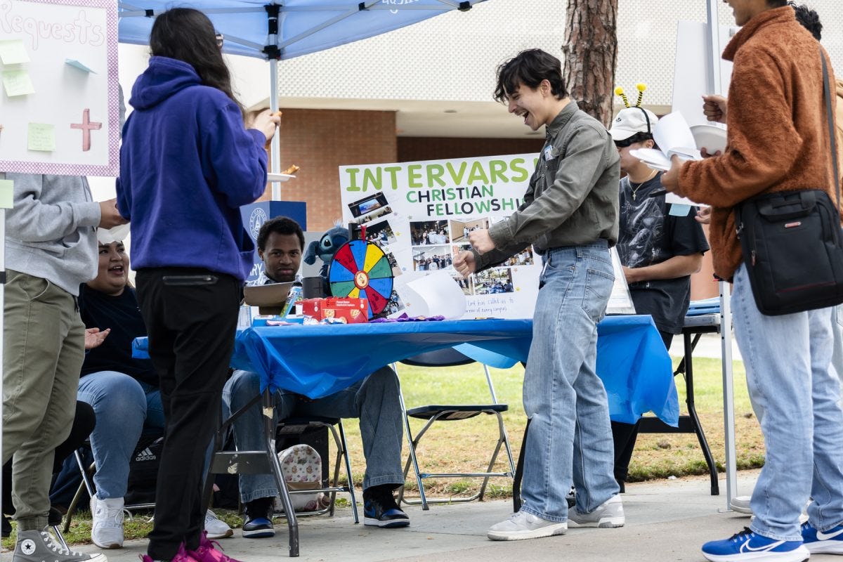 Welding major Nathan Granados (center) spins the wheel at the InterVarsity Christian Fellowship club table at Club Rush on Monday, April 28. The club was established this spring and currently has between 20 and 30 members. (Bret Fast | The Union)