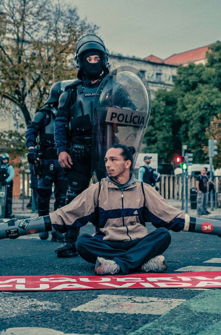 A climate activist sitting down as part of the occupation of the praça do Chile, under vigilance of police forces