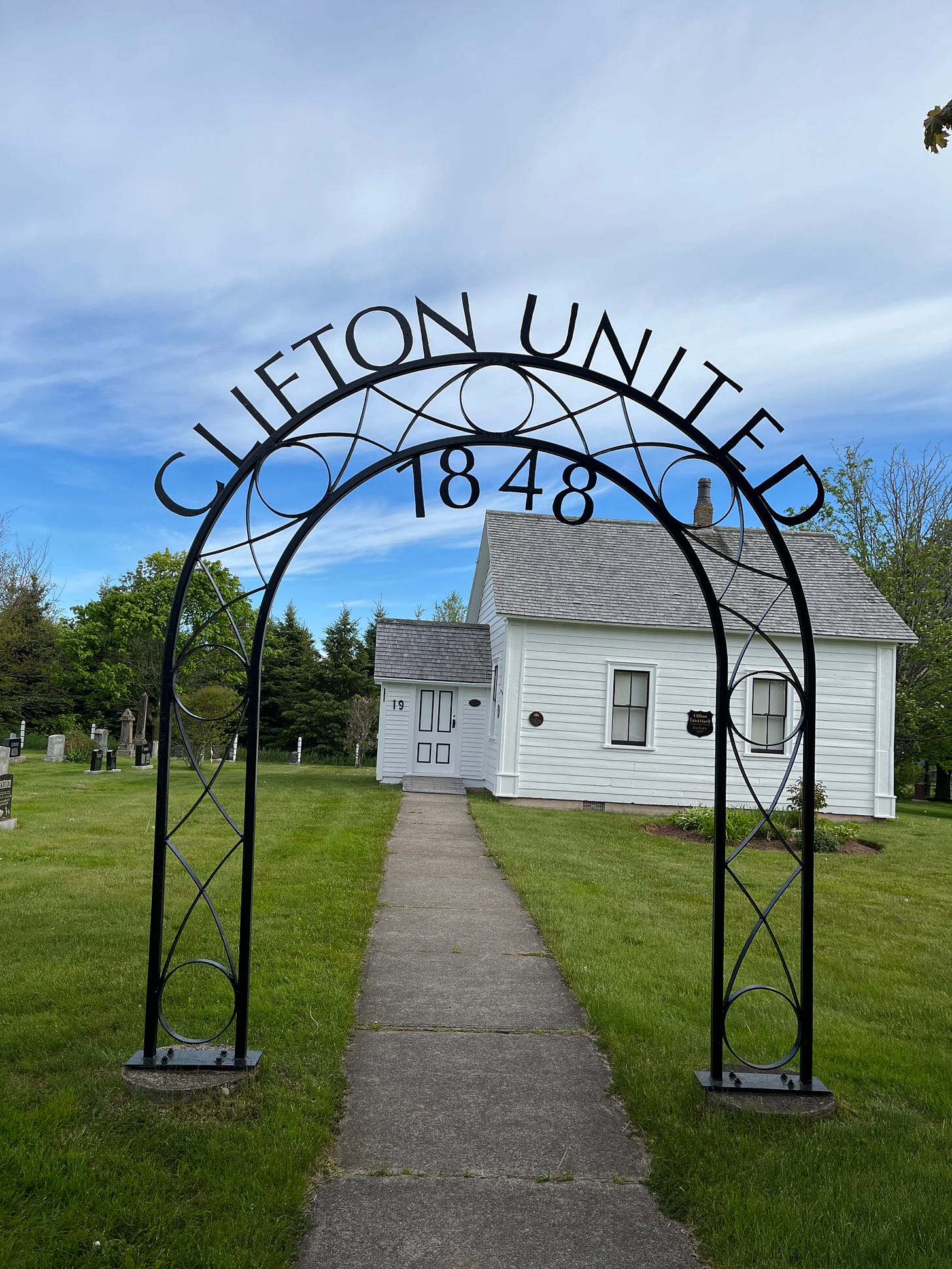 a very small country church behind an iron arch that reads Cliffton United Church 1848 a very small country church behind an iron arch that reads Cliffton United Church 1848
