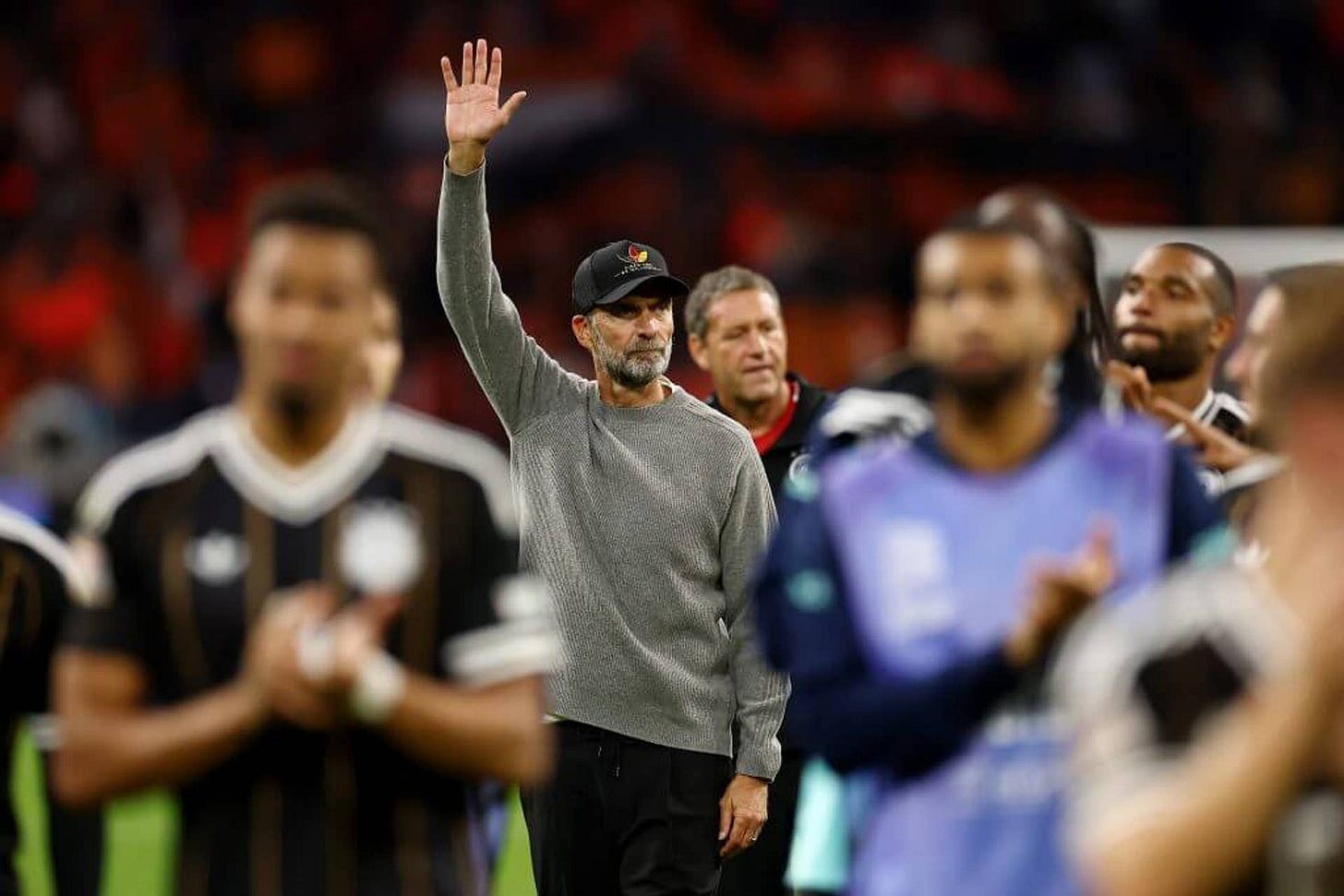 Jurgen Klopp acknowledges the fans after his first game in charge of Germany by raising his right hand. He is wearing a cap and a grey pullover Jurgen Klopp acknowledges the fans after his first game in charge of Germany by raising his right hand. He is wearing a cap and a grey pullover