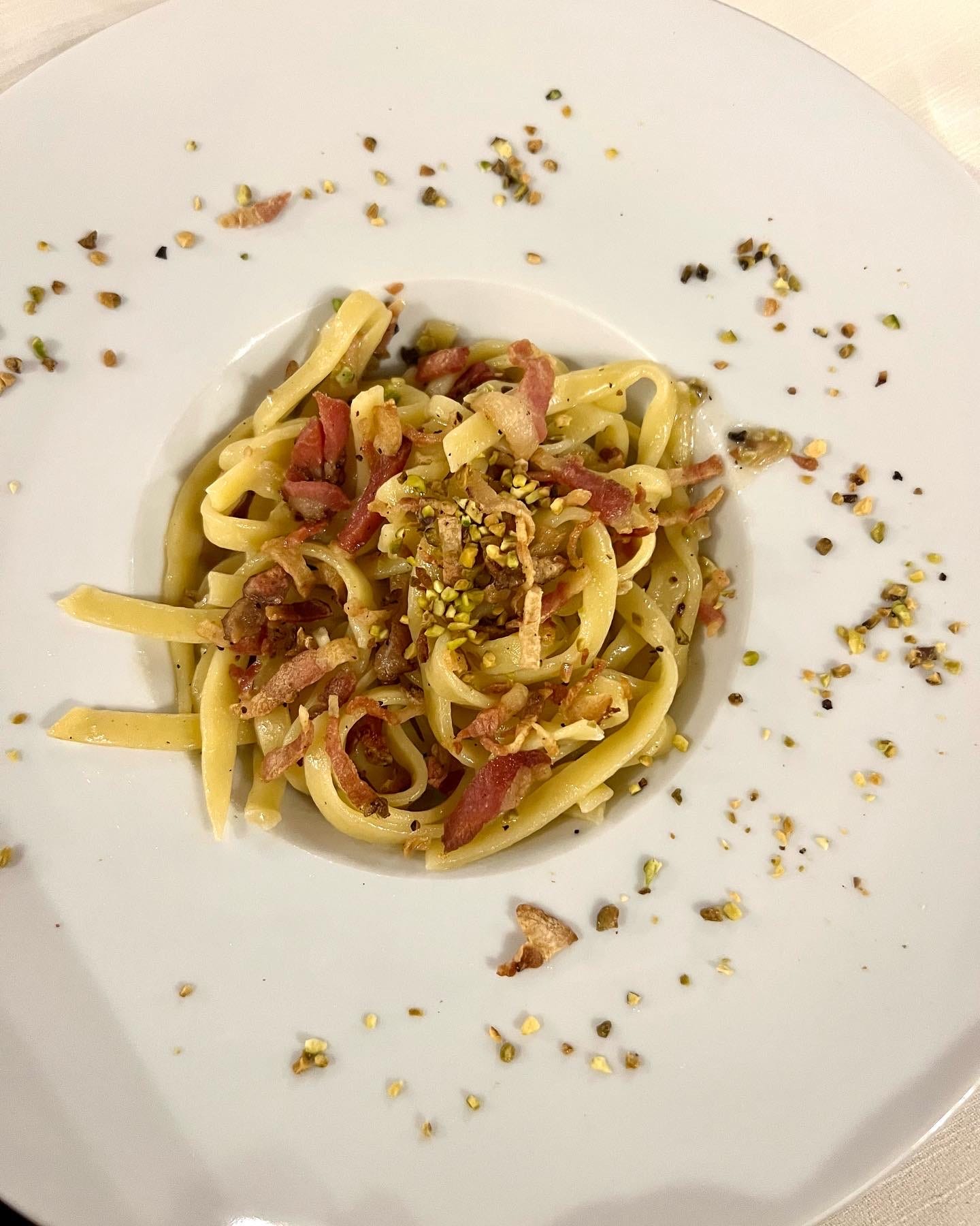 A plate of guanciale and pistachio pasta found in an off-the-path eatery in Bologna. how to find the best food while traveling.