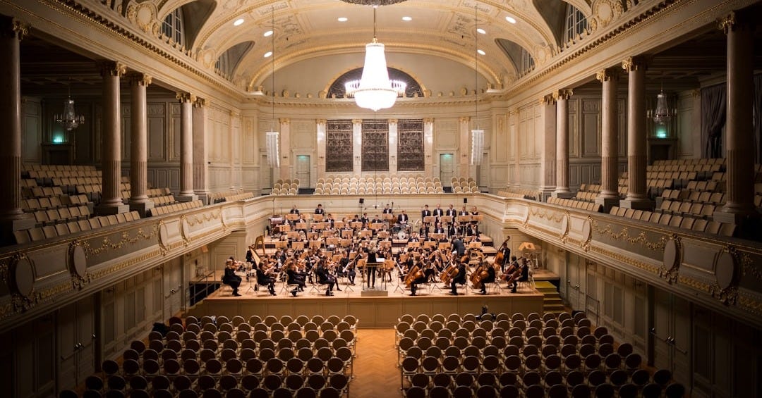 music group performing on stage with empty audience seats