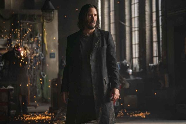 Screencap from Resurrections, Neo set against a machine shop. Off screen, Trinity is in danger. Screencap from Resurrections, Neo set against a machine shop. Off screen, Trinity is in danger.