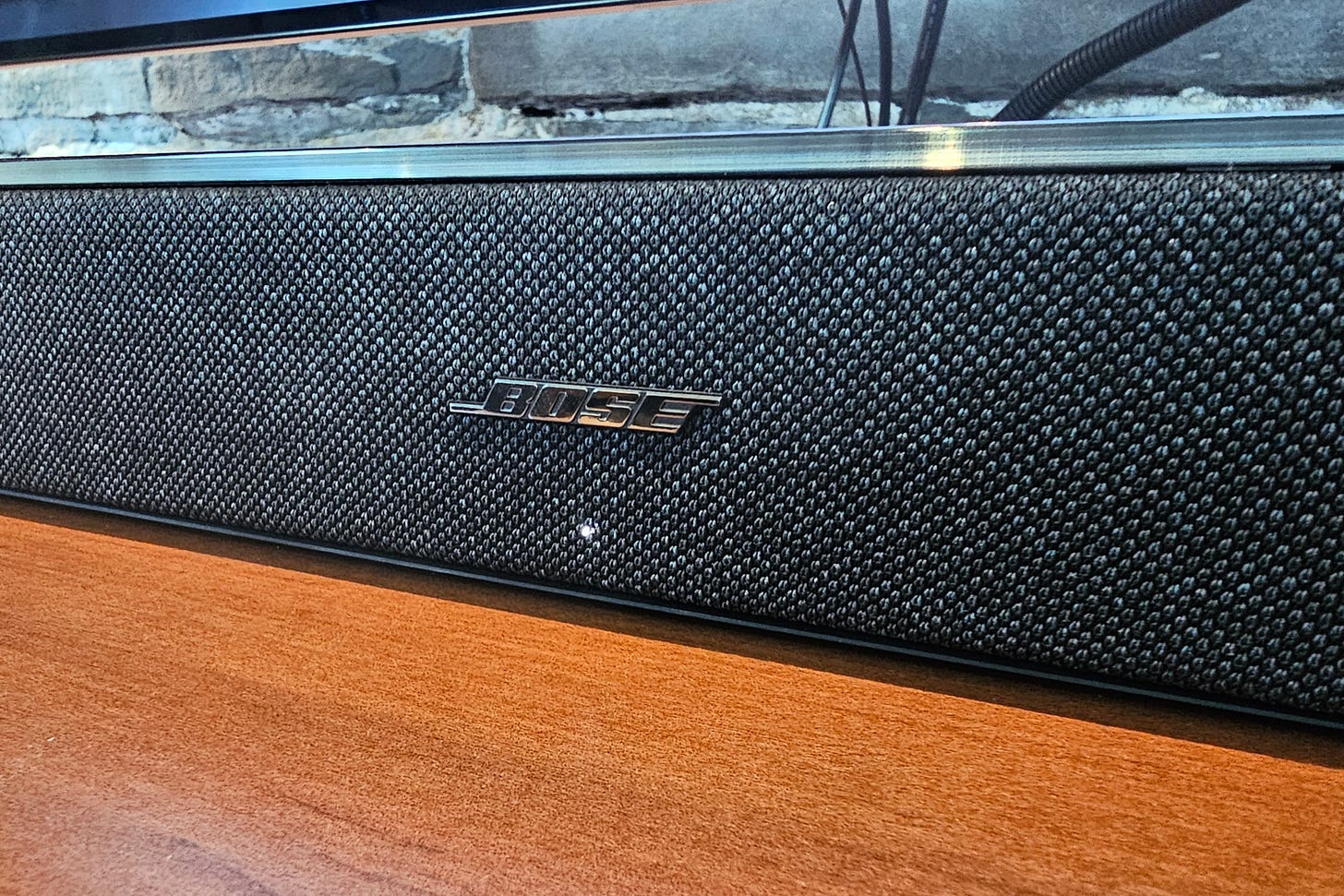 Close up of the Bose logo on the front grille of a Lifestyle Ultra Soundbar.