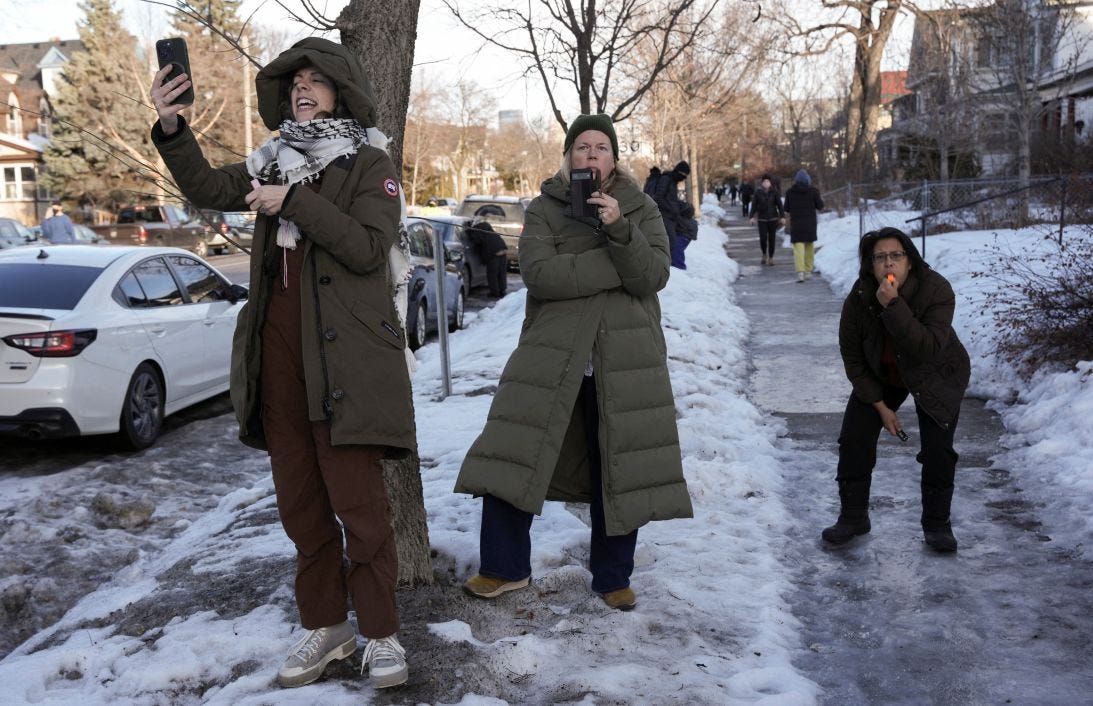Women record as one of them uses a whistle to alert people of the presence of federal agents in the area, days after an ICE agent fatally shot Renee Nicole Good, in Minneapolis on January 13, 2026.