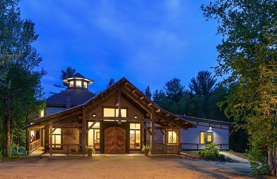 A building with a large front porch and a large building with trees

Description automatically generated with medium confidence