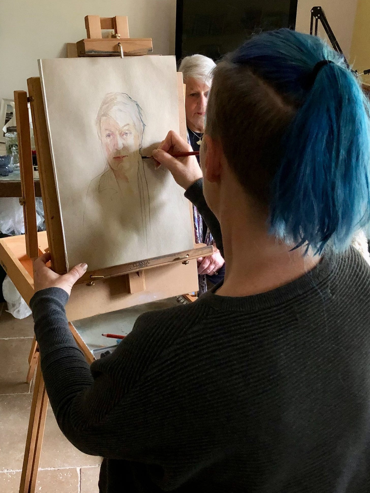 Photo of Gail drawing a portrait, looking over her shoulder as she observes the subject