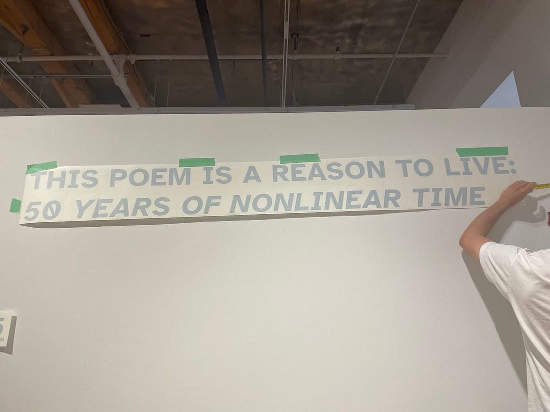 THIS POEM IS A REASON TO LIVE: FIFTY YEARS OF NONLINEAR TIME taped up on a wall