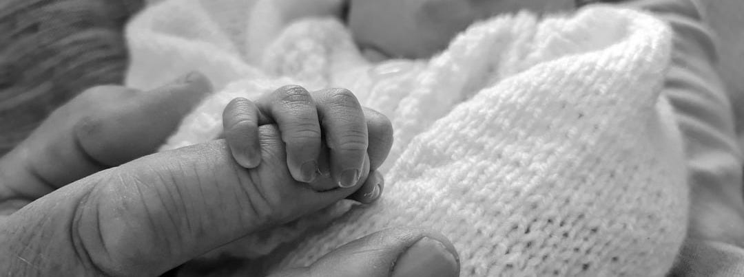 babys feet on white textile
