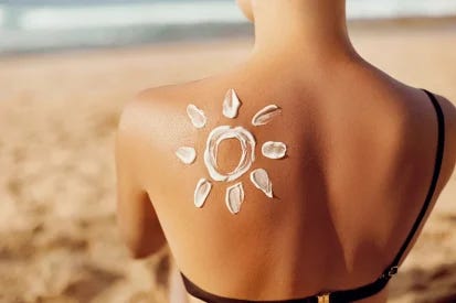 Woman's back with sunscreen creatively applied in a sun design, at the beach