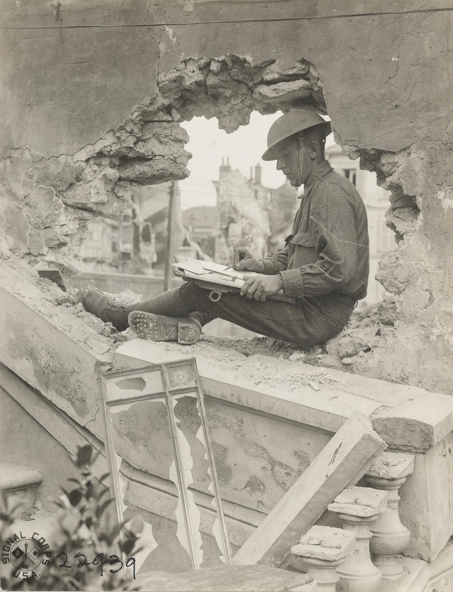 A poignant moment from WWI: a U.S. soldier composes a letter amidst the ruins of a shelled-out wall in Château-Thierry, 1918.