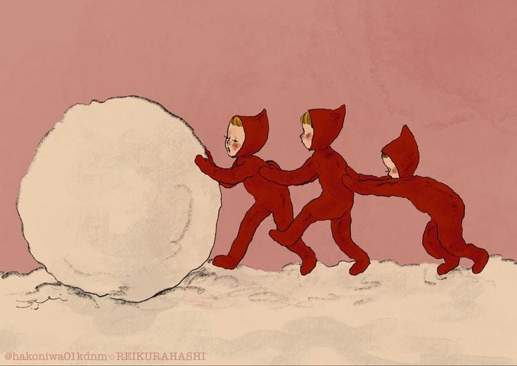 This may contain: three people in red suits are pushing a snowball up the side of a hill