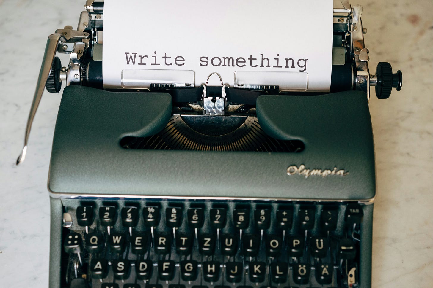 typewriter with a piece of paper that says, "write something"