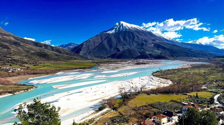 A landscape photo of a wide river through some mountains on a sunny day A landscape photo of a wide river through some mountains on a sunny day