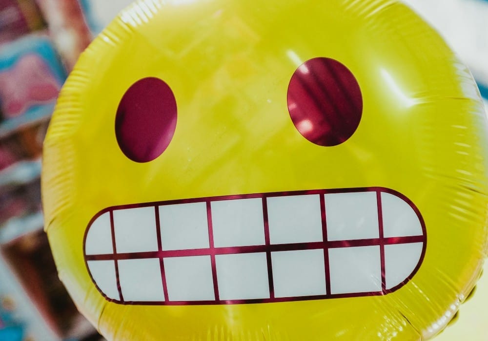Yellow mylar balloon with smiley face emoji that grits its teeth Yellow mylar balloon with smiley face emoji that grits its teeth