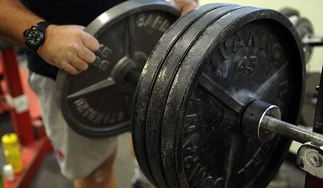 man loading cast-iron plates onto a bar in the gym. 