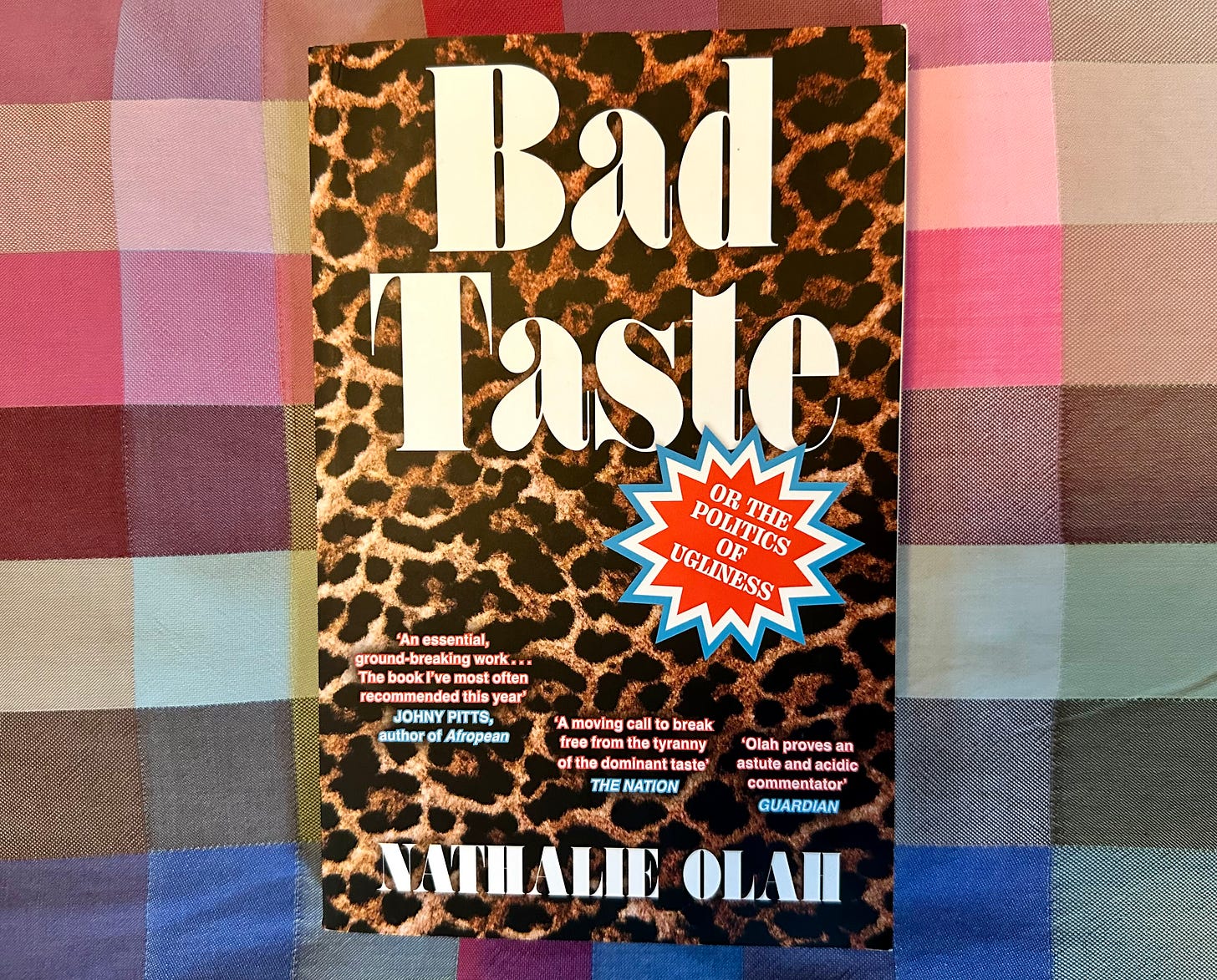 Picture of a book titled “Bad Taste or, the Politics of Ugliness” by Natalie Olah, on a multi-colour rainbow checked cloth. The cover shows the title in giant white serifed font on top of a background of all-over leopard print, which is perhaps an ironic visual reference the way animal prints are sometimes viewed as unsophisticated Picture of a book titled “Bad Taste or, the Politics of Ugliness” by Natalie Olah, on a multi-colour rainbow checked cloth. The cover shows the title in giant white serifed font on top of a background of all-over leopard print, which is perhaps an ironic visual reference the way animal prints are sometimes viewed as unsophisticated