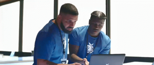 two men are looking at a laptop together . two men are looking at a laptop together .