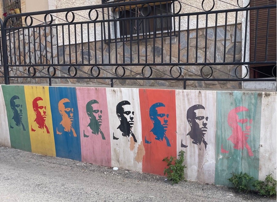 Colourful pop art graffiti on a wall. Above is a black iron railing.