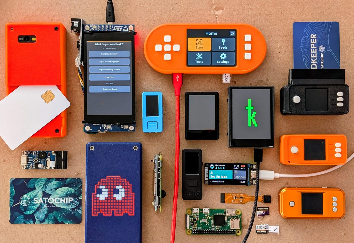 A tabletop covered with more than a dozen DIY bitcoin signing devices in various enclosures, alongside loose components and smartcards. A tabletop covered with more than a dozen DIY bitcoin signing devices in various enclosures, alongside loose components and smartcards.