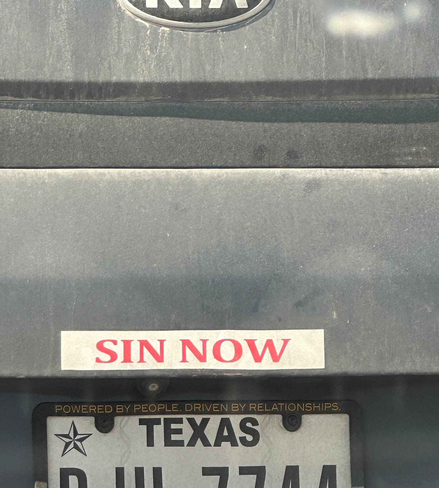 car bumper sticker reads "sin now"