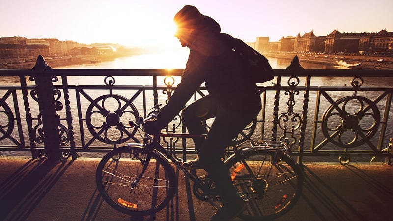 a man riding a bicycle across a river bridge