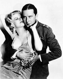 A man in a suit embraces a blonde starlet, whose glamorous velvet dress hangs provocatively low.