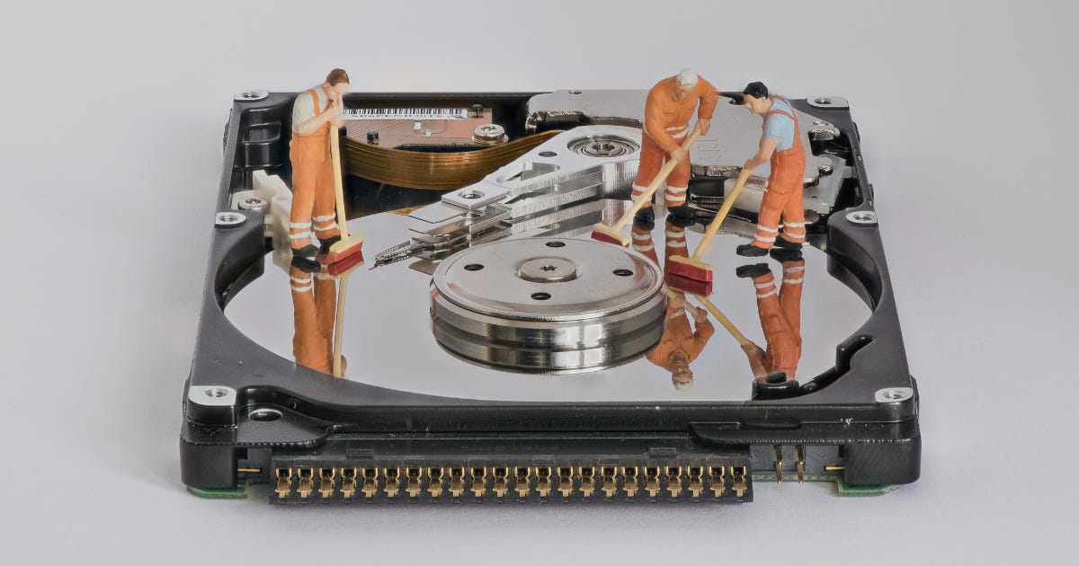 Little human figurines have been placed on a hard drive, as if cleaning the machine.