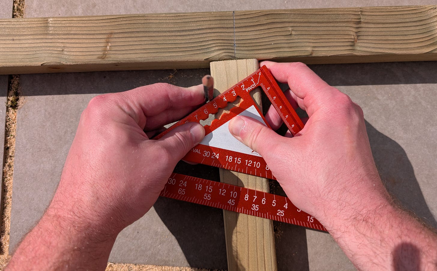 Woodworker using a carpenter's square to pivot and find the center line of a wooden beam