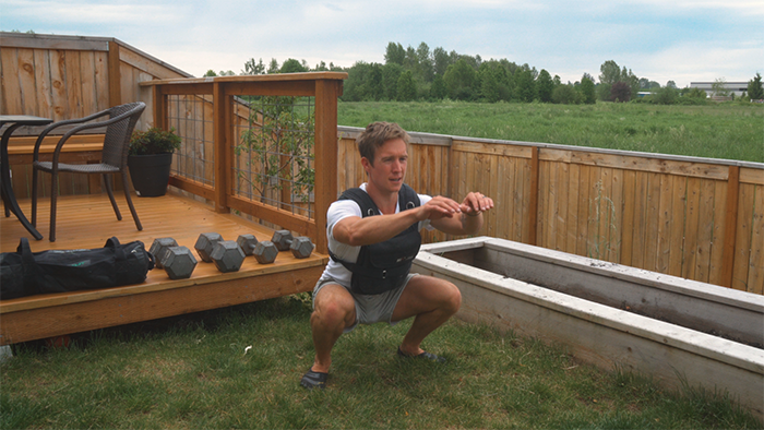 air squats wearing a weighted vest